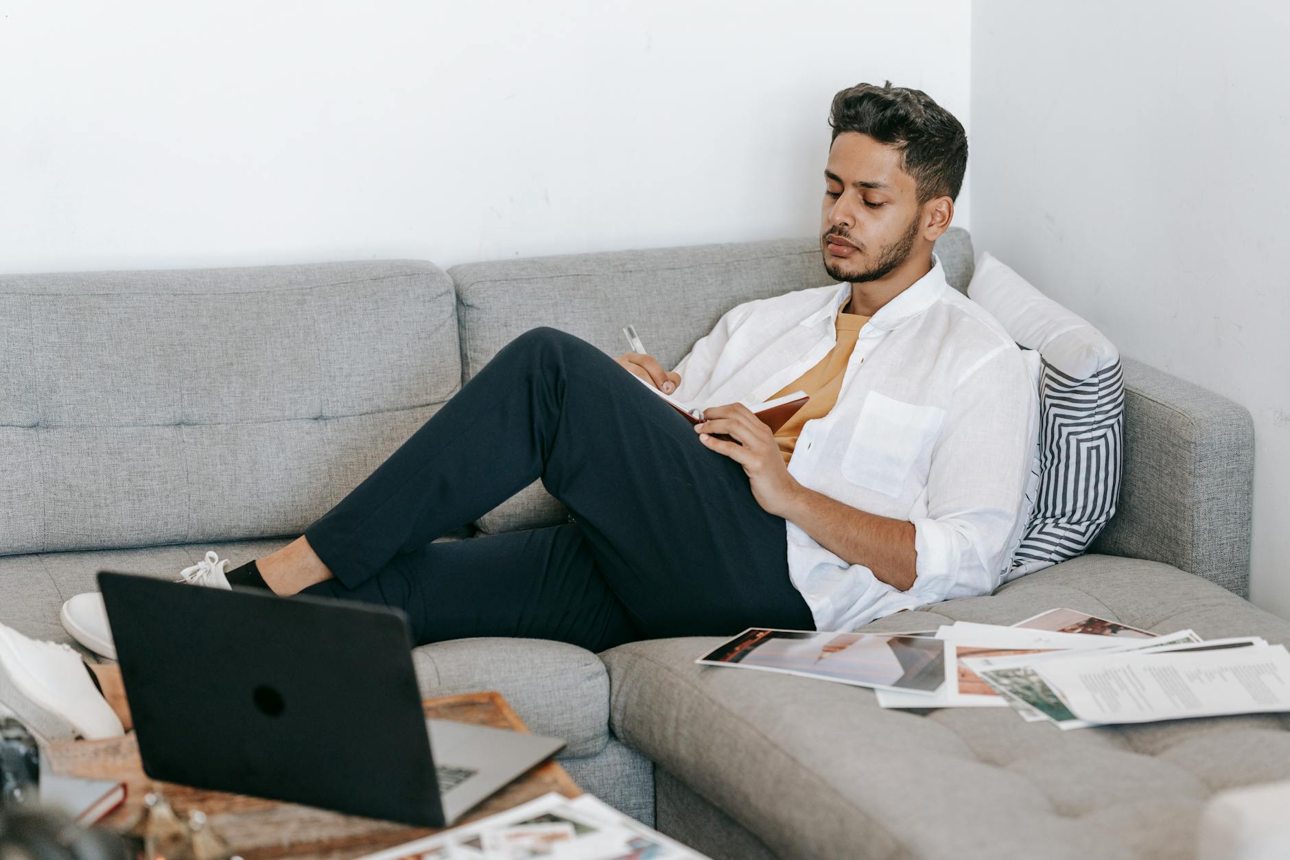 man taking notes in notebook near laptop
