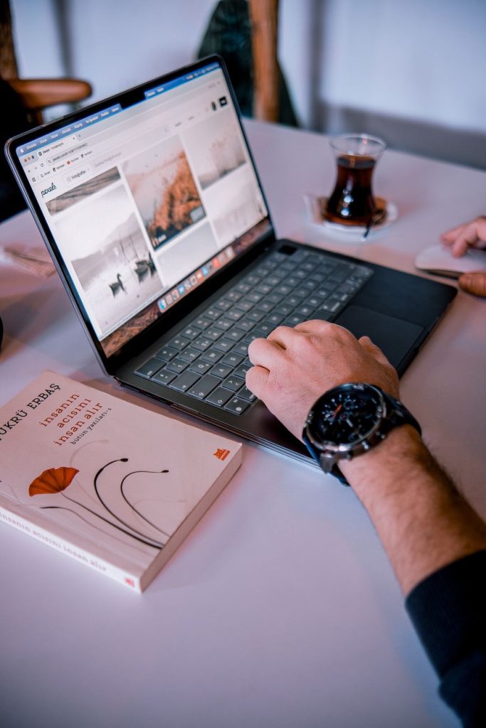 Current image: man using laptop with coffee and book nearby